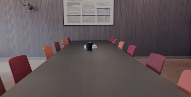 A long meeting table with chairs and a screen on a wall.